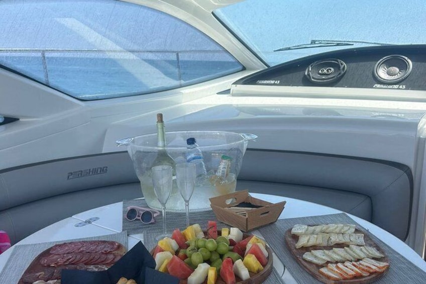 A boat's interior with a table set for a meal, including fruits, bread, and a bottle of champagne. 5