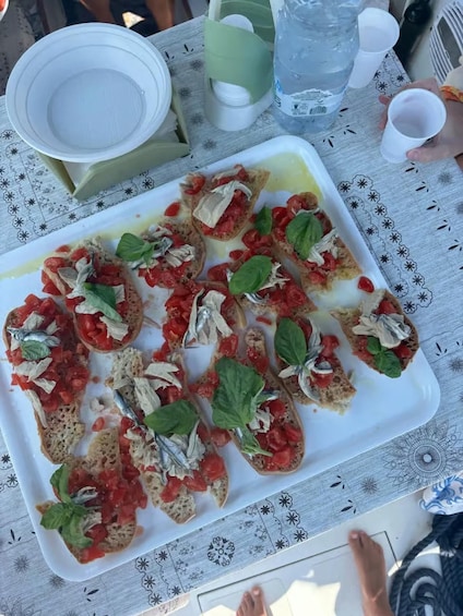 A table with a plate of bruschetta topped with tomatoes, basil, and anchovies. 2