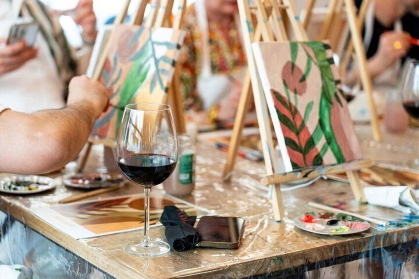 An art workshop with easels, paintbrushes, and a wine glass on a table. 2