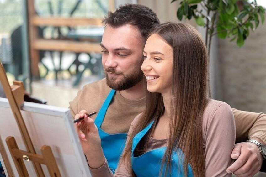Two people painting on a canvas in an indoor setting. 1