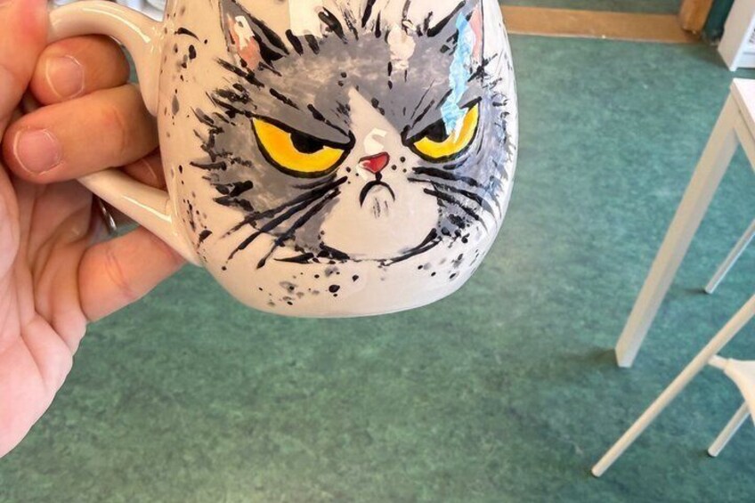 A hand holding a mug with a cat design. 3