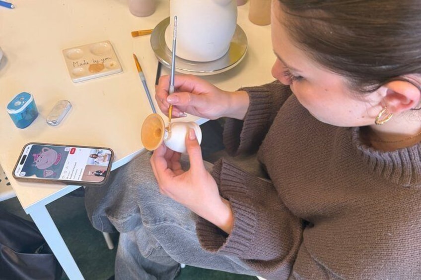 A person painting a ceramic cup. 4