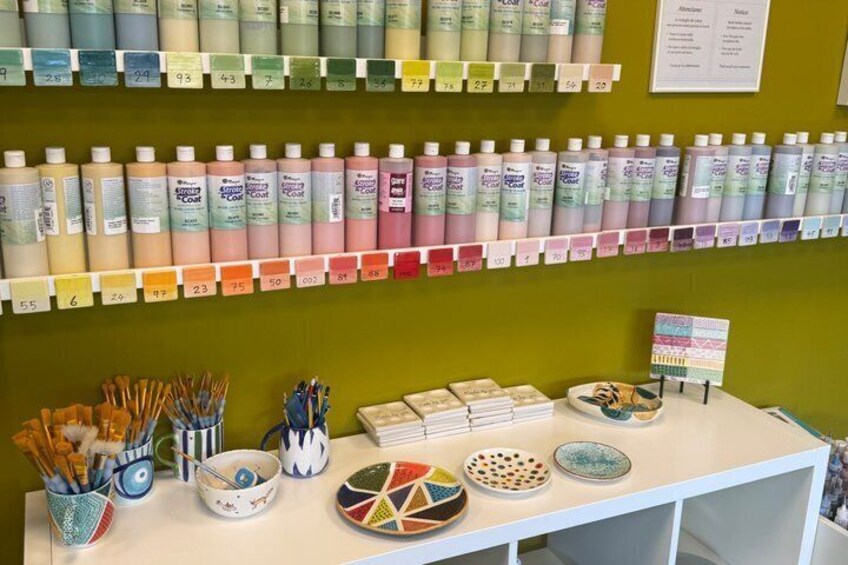 A display of nail polish bottles, paintbrushes, bowls, and a small painting on a table. 1