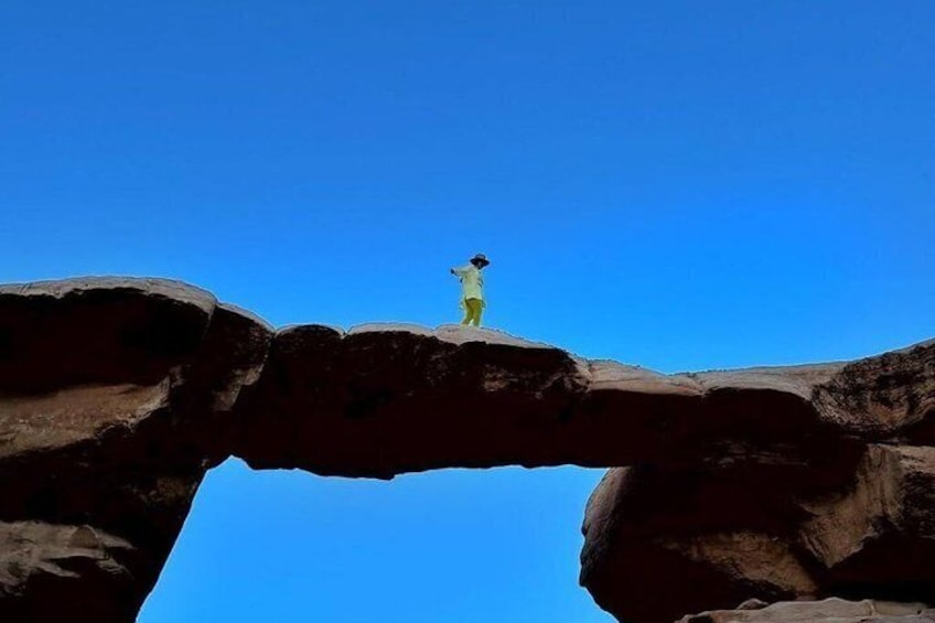 A person standing on a rock formation with a clear blue sky in the background. 5
