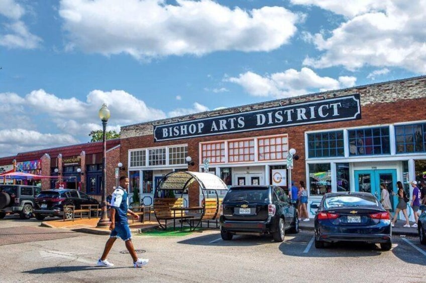 A street scene with a building labeled 'Bishop Arts District,' cars parked in front, and a pedestrian crossing the street. 2