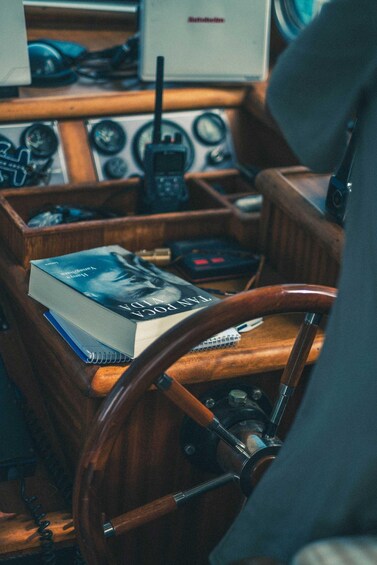 A boat's control panel with a book, a steering wheel, and various gauges. 2