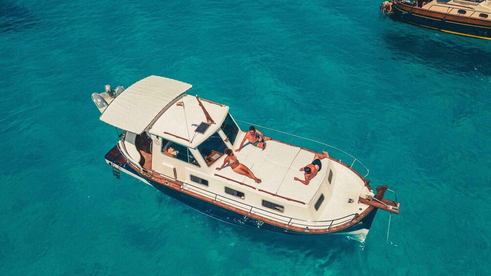 A boat with a covered deck and two people sunbathing. 5