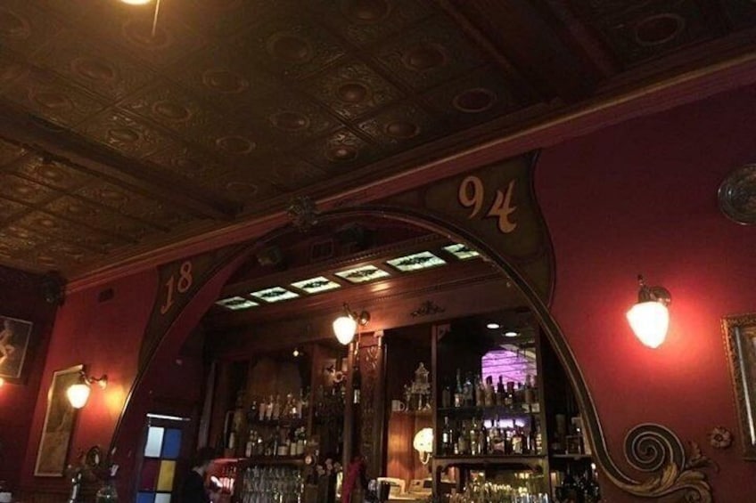 An ornate bar with a red wall and a ceiling with intricate designs. 2