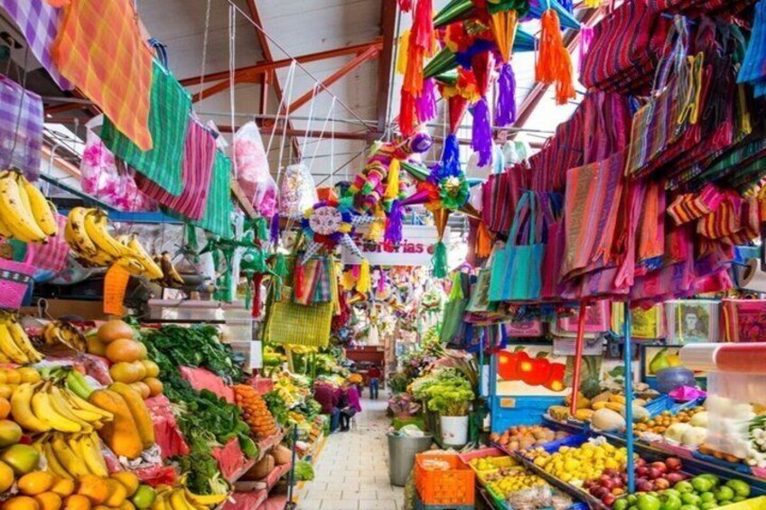A vibrant market with colorful textiles, fruits, and vegetables on display. 5