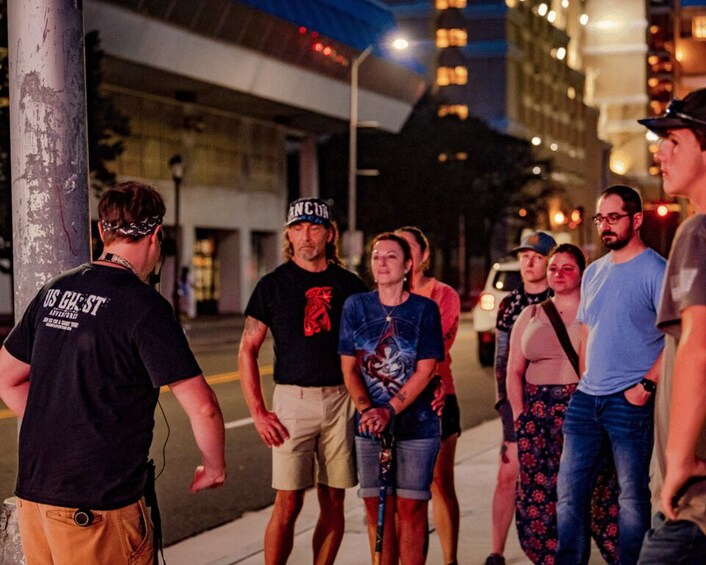 A group of people standing on a city street at night. 2