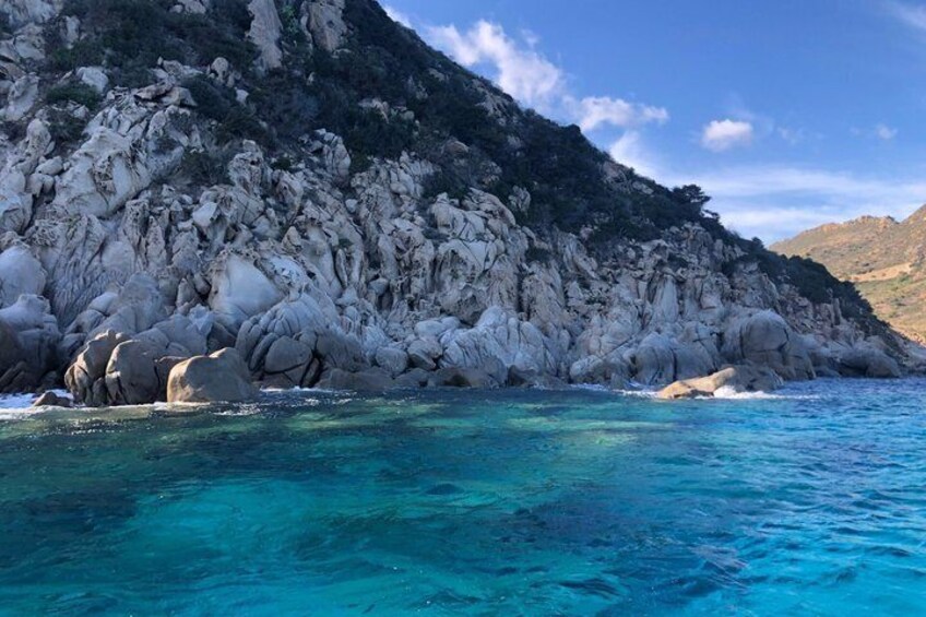 A coastal landscape with rocky cliffs and clear turquoise water. 3