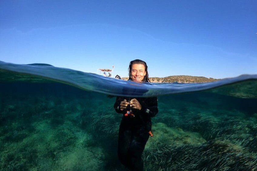 A person underwater with a clear view of the ocean floor and a distant boat. 5