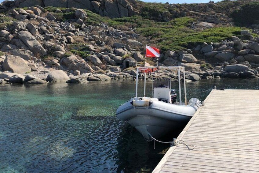 A boat docked at a rocky shore with a wooden pier. 4