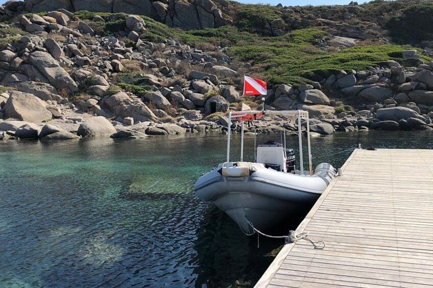A boat docked at a wooden pier with a rocky shoreline in the background. 4