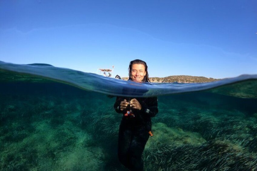 A person underwater with a clear view of the ocean floor and a distant boat. 5