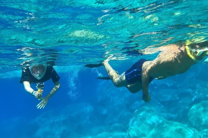 Two people swimming underwater in clear blue water. 1