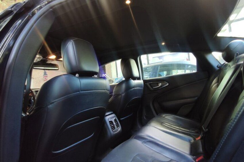 The interior of a car with black leather seats, a sunroof, and a center console with cup holders. 3