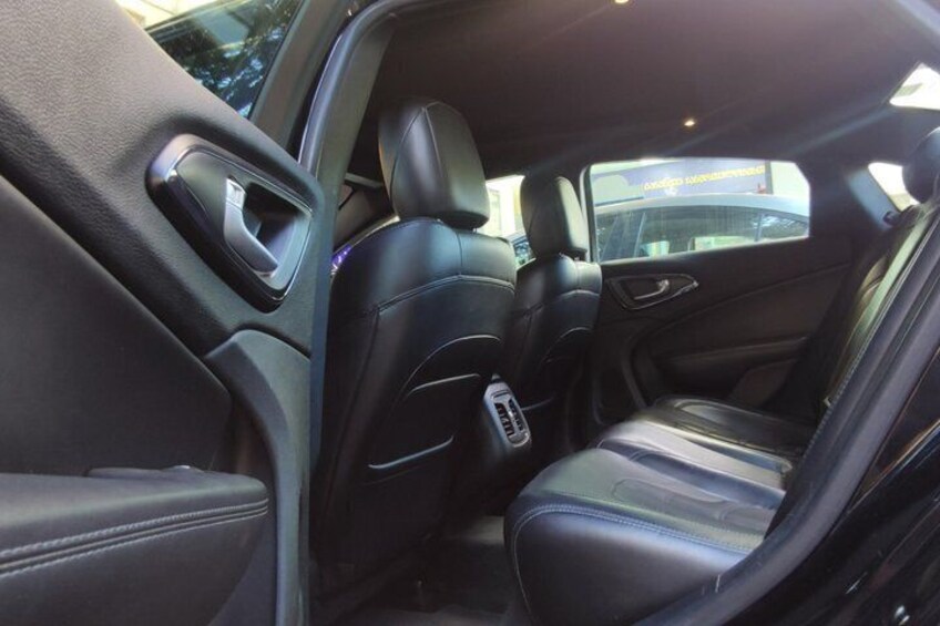A car's interior with black leather seats, a center console, and a sunroof. 4
