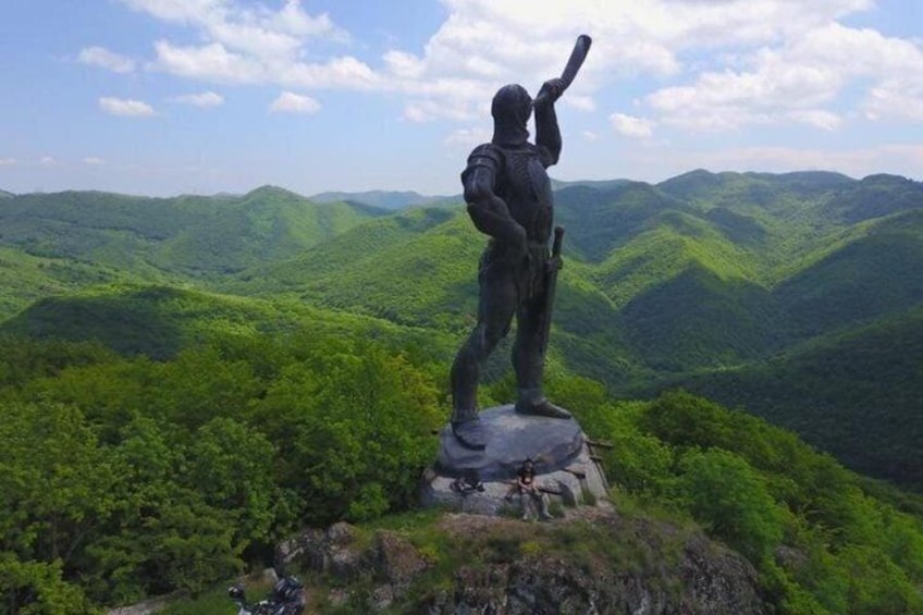 A statue of a person with a rifle on a hill overlooking a valley. 3