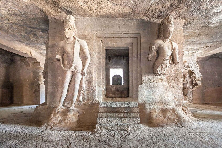 Ett uråldrigt tempel som är inbyggt i en grotta, med två stående statyer på var sin sida om en central ingång. 5