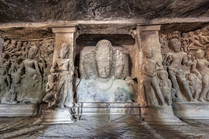 Ett tempel som är uthugget ur berget, med en central Buddha-staty och mindre statyer samt detaljerade skulpturer på vardera sidan. 1
