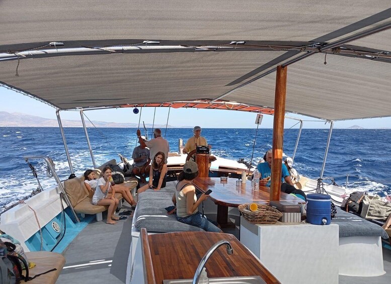 A sailboat with people on deck, a wooden table, and a blue barrel. 4