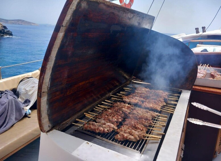 A barbecue grill with skewers of meat, a lifebuoy, and a boat in the background. 5