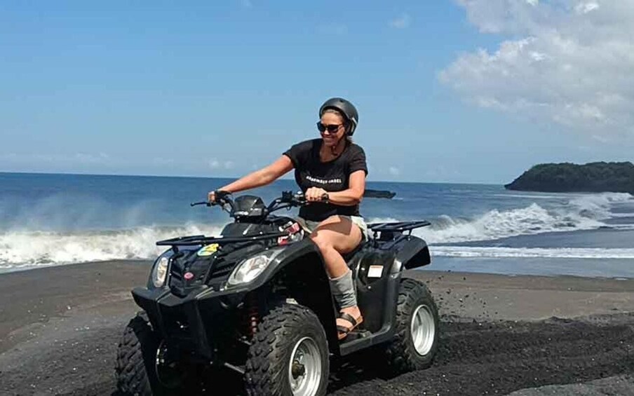 A person riding an ATV on a beach with waves in the background. 5