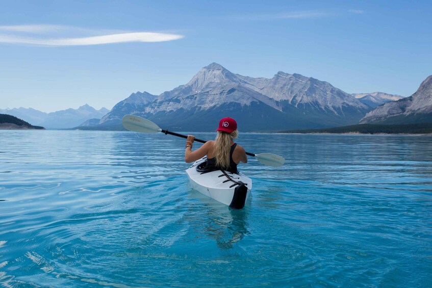 A person kayaking on a calm lake with mountains in the background. 4