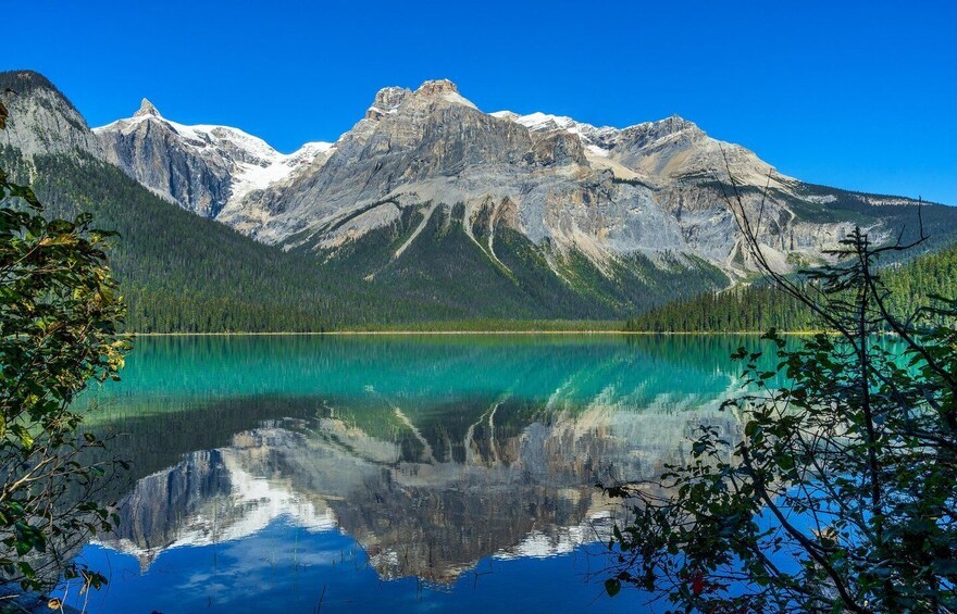 A mountain lake with clear turquoise water reflecting the surrounding peaks and forest. 5