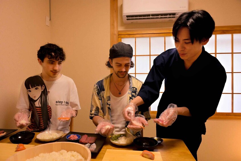 Three people preparing food, wearing gloves, with bowls and ingredients on a table. 1