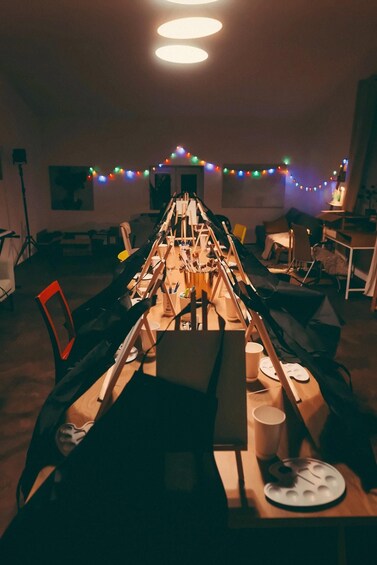 Ett rum med ett långt bord uppdukat för ett evenemang, dekorerat med ljusslingor och diverse föremål. 5