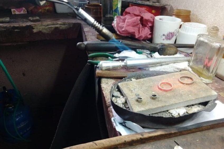 A cluttered workspace with tools, a metal container, and a bottle. 5
