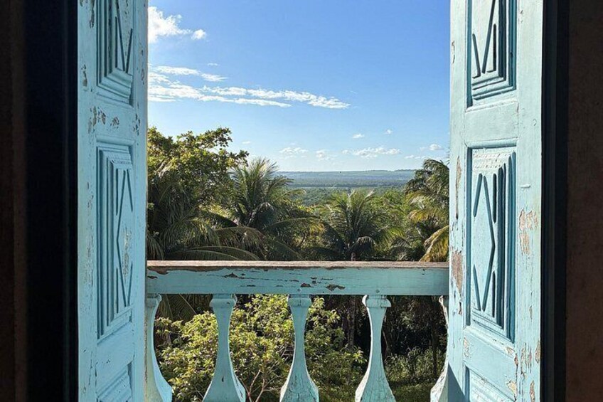 A blue door with a balcony overlooking a landscape with trees and a distant view. 5