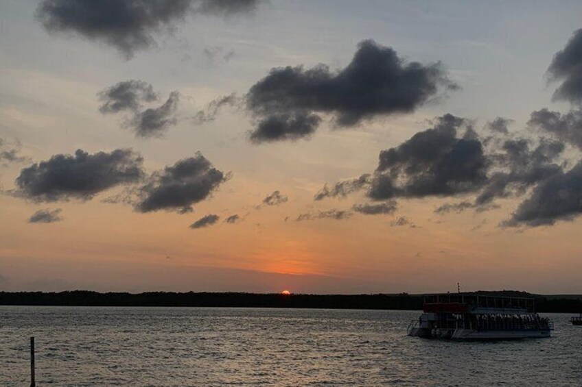 A sunset over a body of water with a boat and a distant shoreline. 5