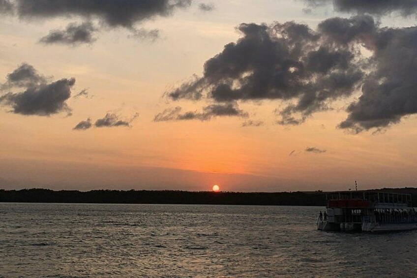 A sunset over a body of water with a boat on the right. 3
