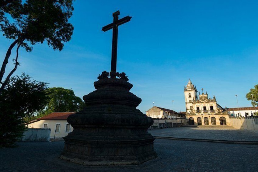 A stone cross in the foreground with a church in the background. 1