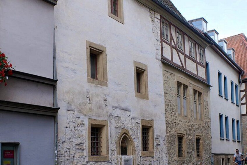 A historic building with a stone facade, multiple windows, and a traditional timber-framed upper story. 5