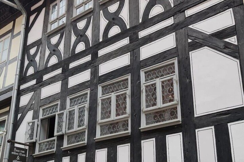 A half-timbered building with intricate window designs and a signboard. 4