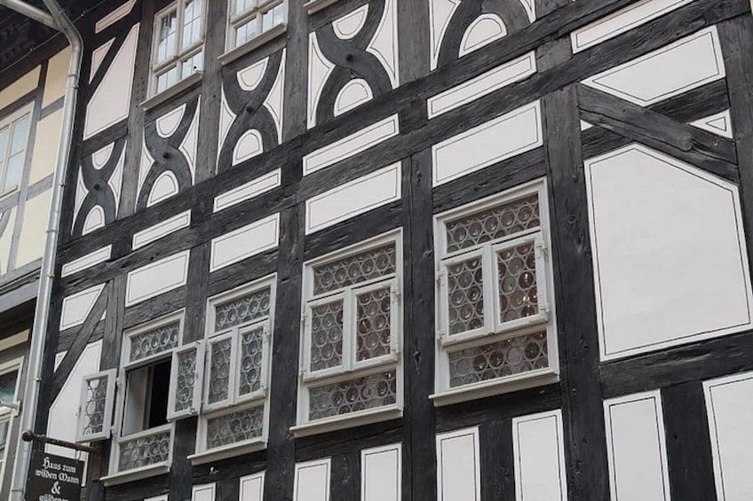 A half-timbered building with intricate window designs and a signboard. 4