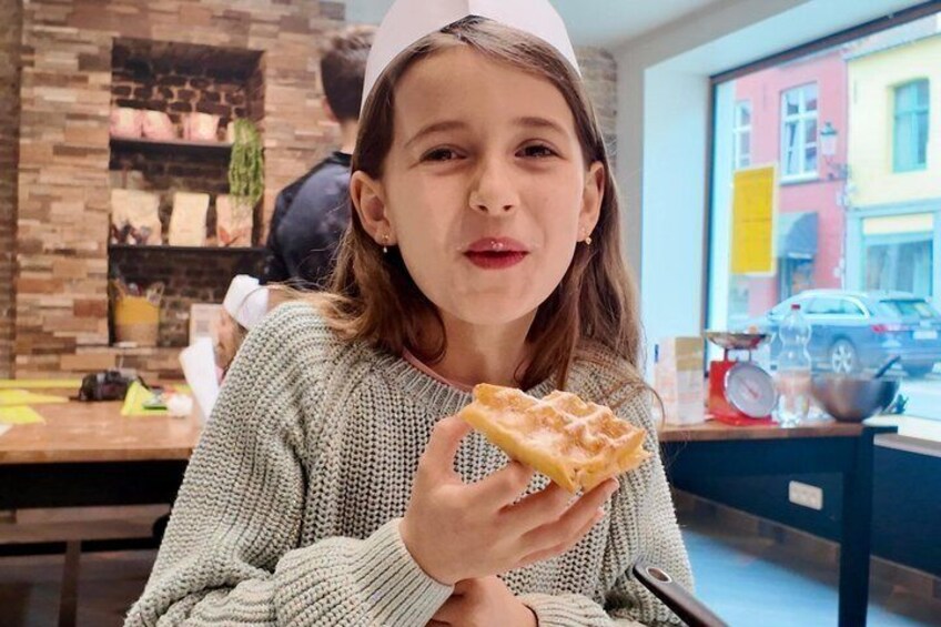 A person holding a square pastry in a cafe with brick walls and a window view. 1