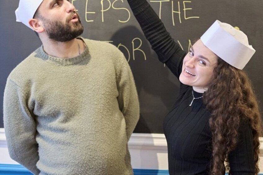 Two people in front of a blackboard with partially visible text. 3