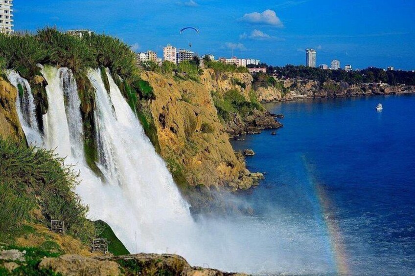 A waterfall cascading into a body of water, with a rainbow visible in the mist. 4