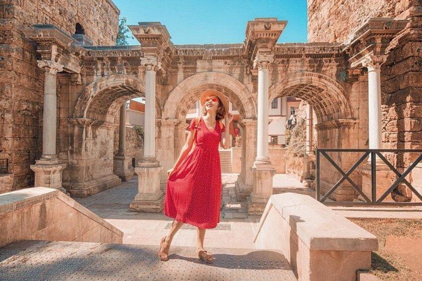 A person in a red dress walking through an ancient stone archway. 1