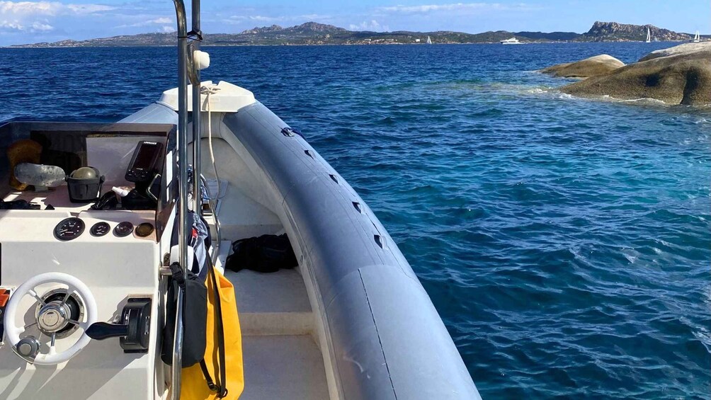A boat on calm waters with rocky outcrops and distant land in the background. 2