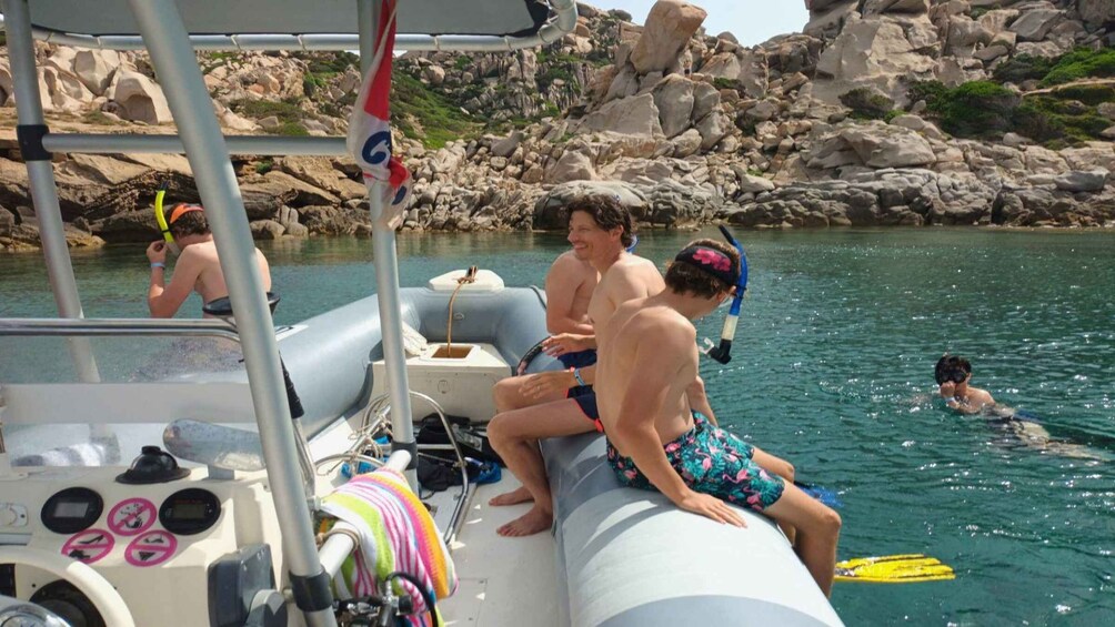 People on a boat in a rocky coastal area with clear water. 3