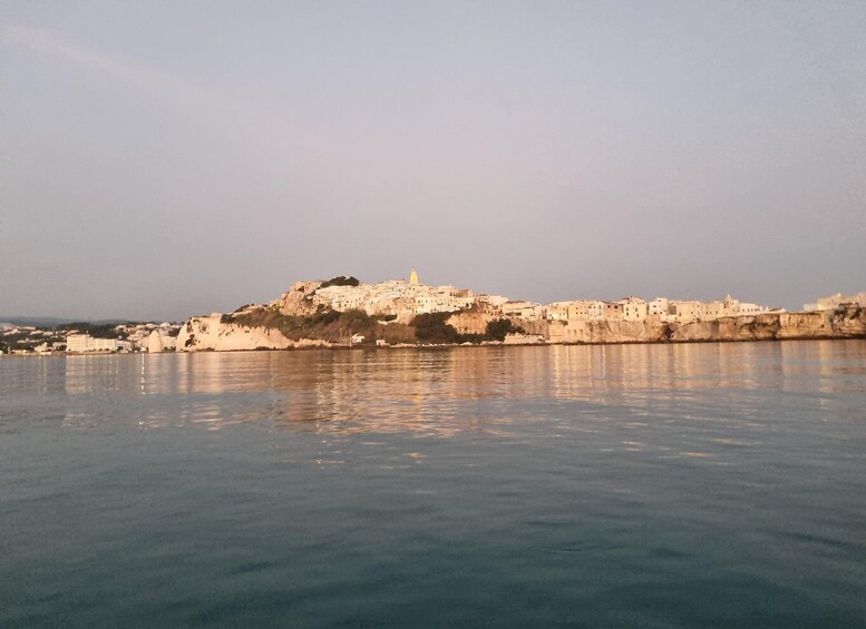 A coastal cityscape with a prominent hilltop structure and a body of water in the foreground. 5