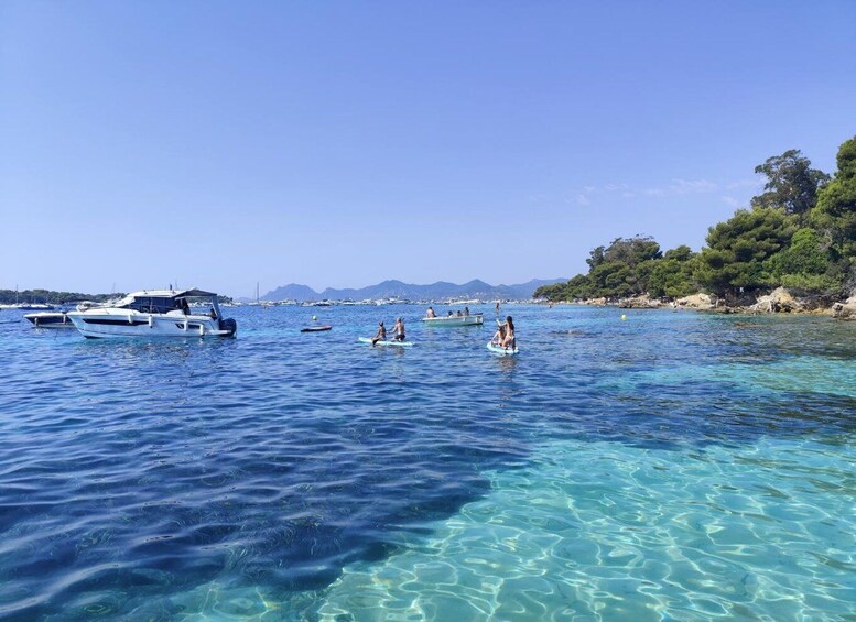 A clear blue sea with boats and people on water sports. 2