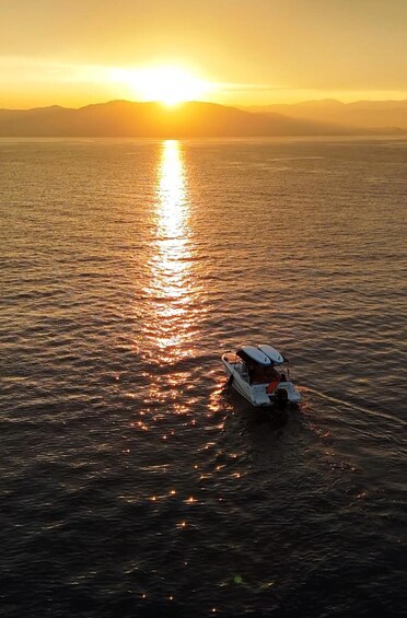 A boat on a calm sea during sunset with mountains in the background. 3