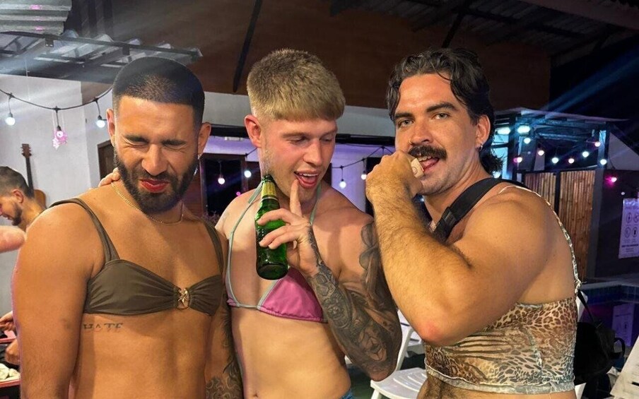 Three people in a bar setting, one holding a bottle. 2
